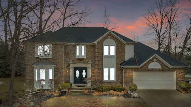 view of front facade featuring brick siding, driveway, an attached garage, and roof with shingles