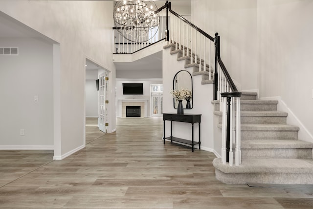 entrance foyer with visible vents, a fireplace, baseboards, and wood finished floors