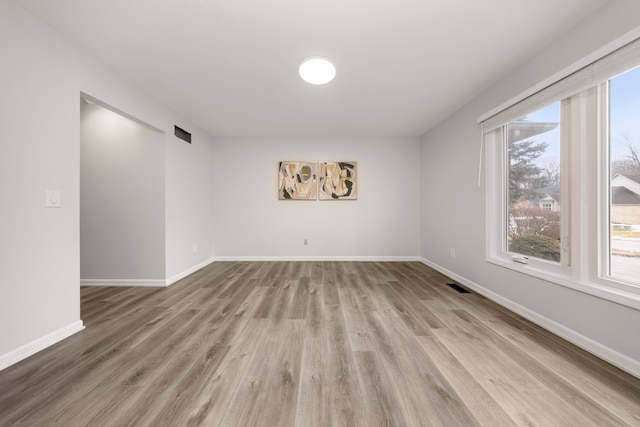 empty room with baseboards, visible vents, and light wood-style floors