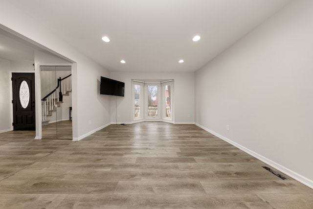 unfurnished living room featuring light wood-style flooring, stairway, visible vents, and recessed lighting