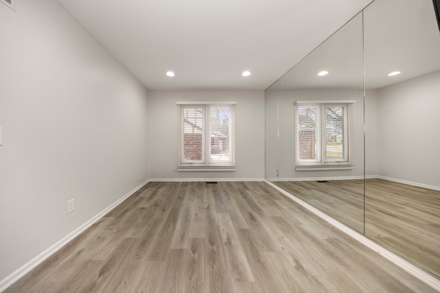 empty room featuring baseboards, light wood-type flooring, and recessed lighting