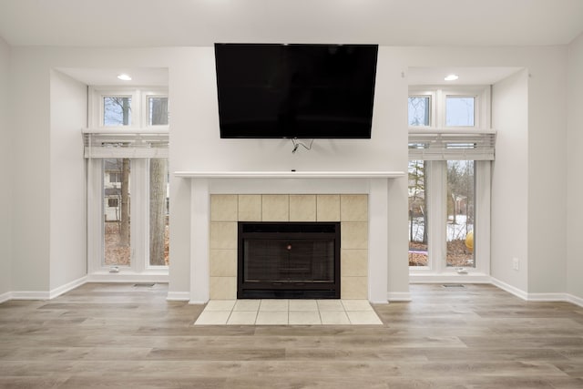 room details featuring visible vents, baseboards, a tiled fireplace, and wood finished floors