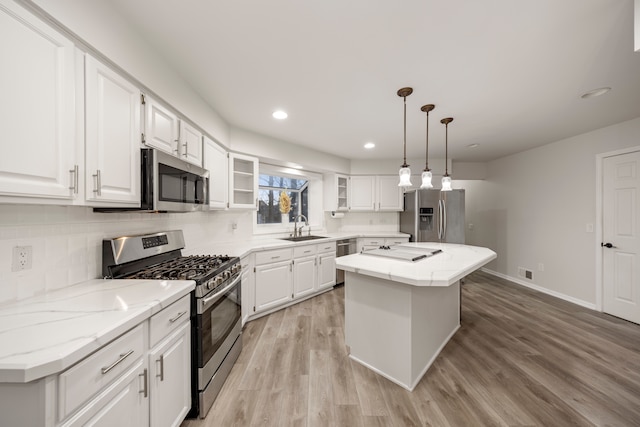 kitchen with a center island, stainless steel appliances, decorative backsplash, white cabinets, and light wood-type flooring