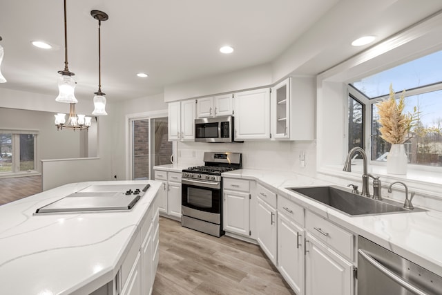 kitchen featuring appliances with stainless steel finishes, a sink, white cabinetry, and light stone countertops