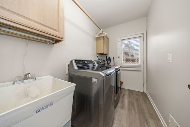 laundry room with cabinet space, visible vents, washer and clothes dryer, light wood-style flooring, and a sink