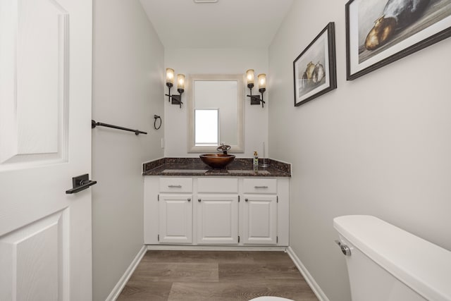 bathroom with toilet, baseboards, wood finished floors, and vanity