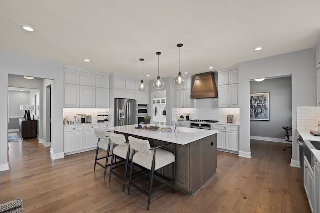 kitchen with hardwood / wood-style flooring, stainless steel appliances, light countertops, a kitchen bar, and custom range hood