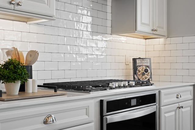 kitchen with light countertops, appliances with stainless steel finishes, white cabinetry, and decorative backsplash