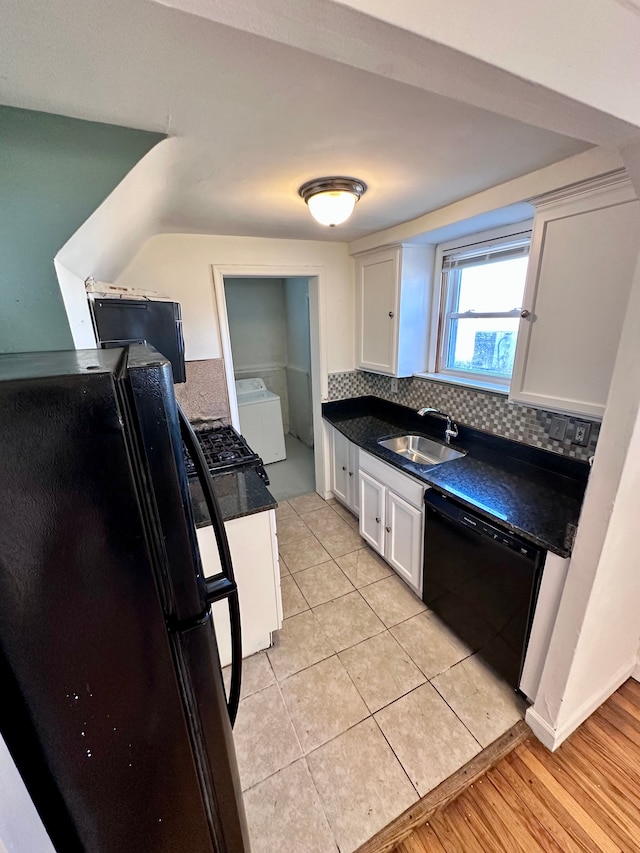 kitchen featuring washer / dryer, dark countertops, black appliances, white cabinetry, and a sink