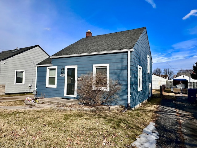 back of house with a chimney, fence, and roof with shingles