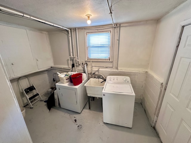 clothes washing area featuring a textured ceiling, separate washer and dryer, and a sink