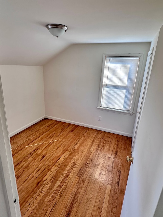 additional living space featuring light wood-type flooring, vaulted ceiling, and baseboards