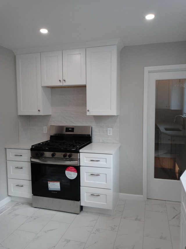 kitchen with stainless steel gas stove, marble finish floor, light countertops, a sink, and recessed lighting