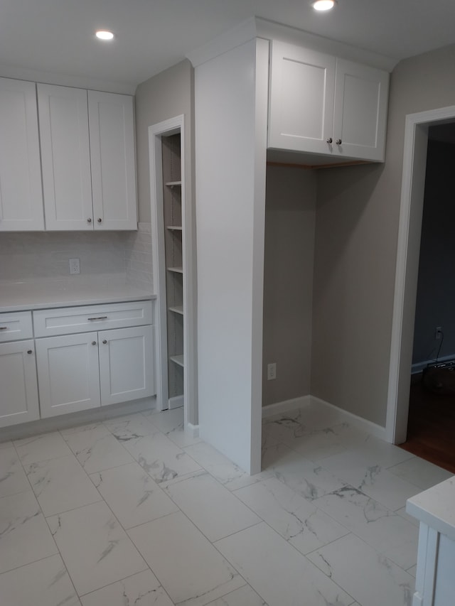 interior space featuring recessed lighting, white cabinetry, baseboards, marble finish floor, and light countertops