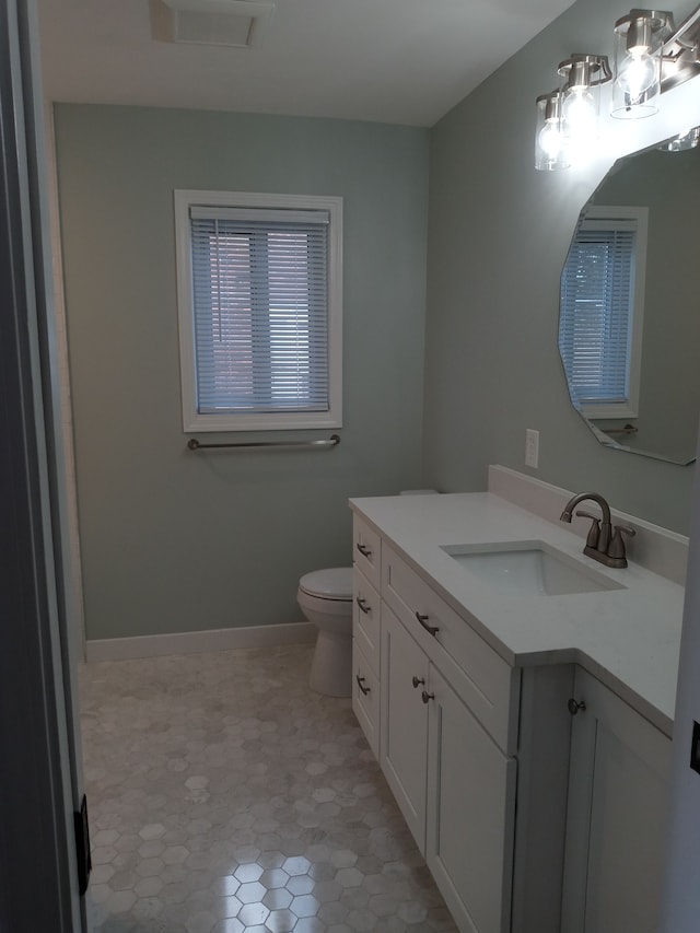 bathroom with baseboards, visible vents, vanity, and toilet