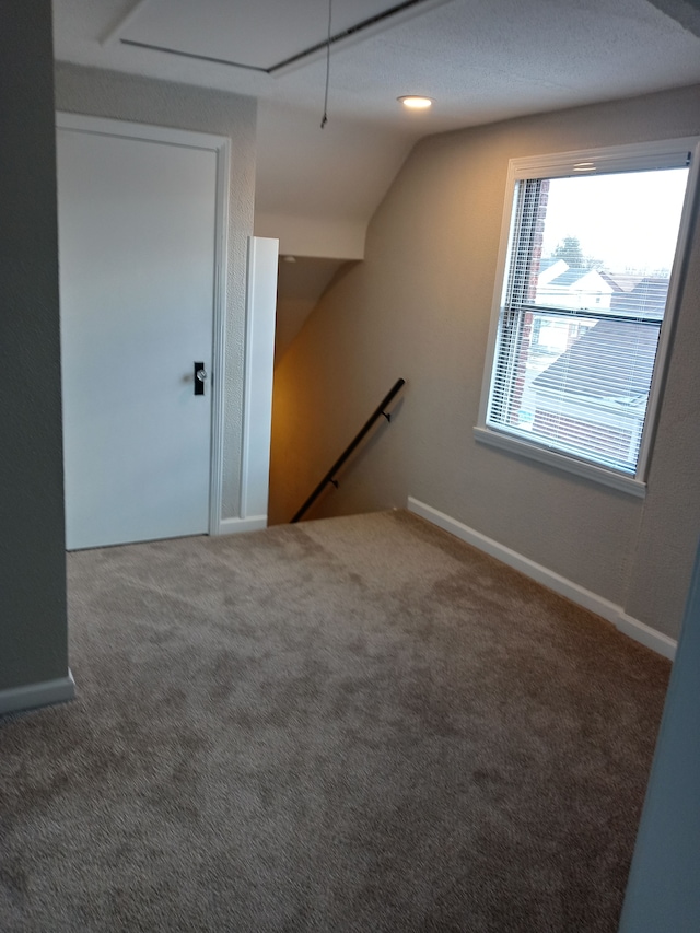 additional living space with attic access, lofted ceiling, baseboards, and carpet