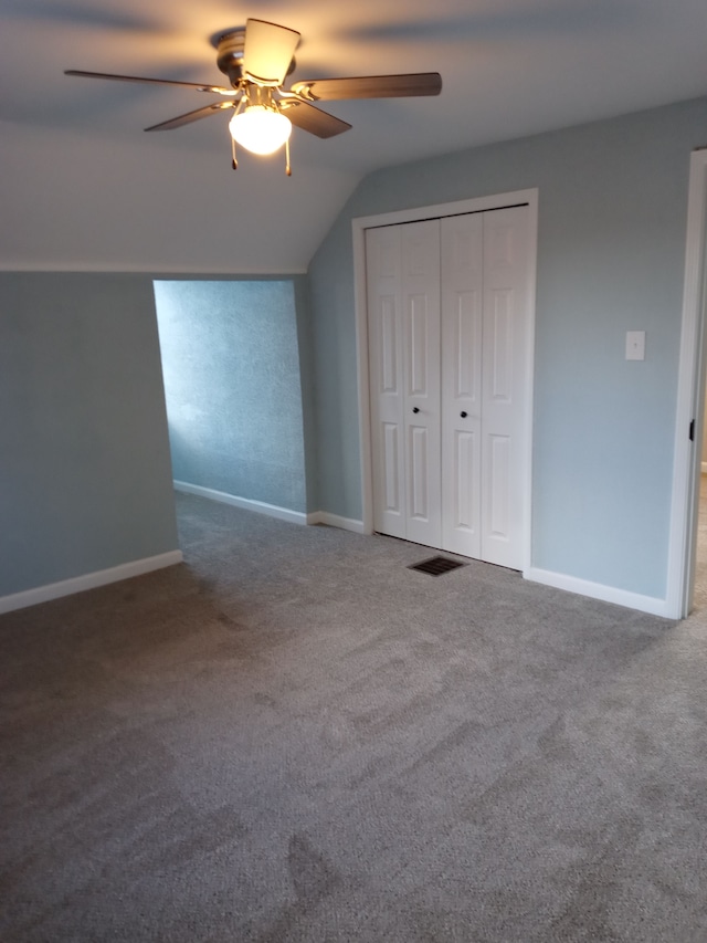 unfurnished bedroom featuring lofted ceiling, a closet, carpet, and baseboards