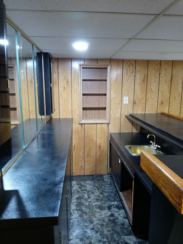 bar featuring wood walls, a sink, and a paneled ceiling