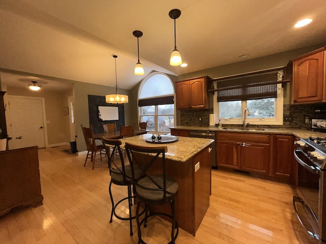 kitchen featuring lofted ceiling, a sink, a center island, dishwasher, and range with gas cooktop