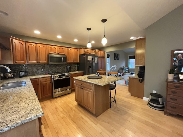 kitchen featuring stainless steel appliances, light wood-type flooring, a sink, and a breakfast bar area