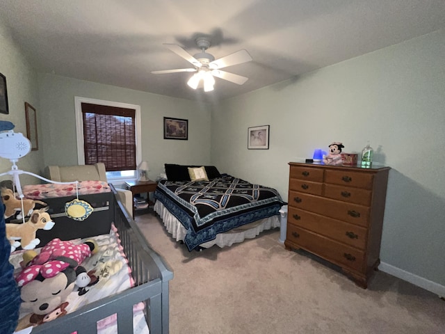 bedroom featuring light carpet, a ceiling fan, and baseboards