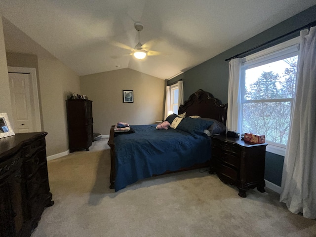 bedroom featuring lofted ceiling, baseboards, a ceiling fan, and light colored carpet