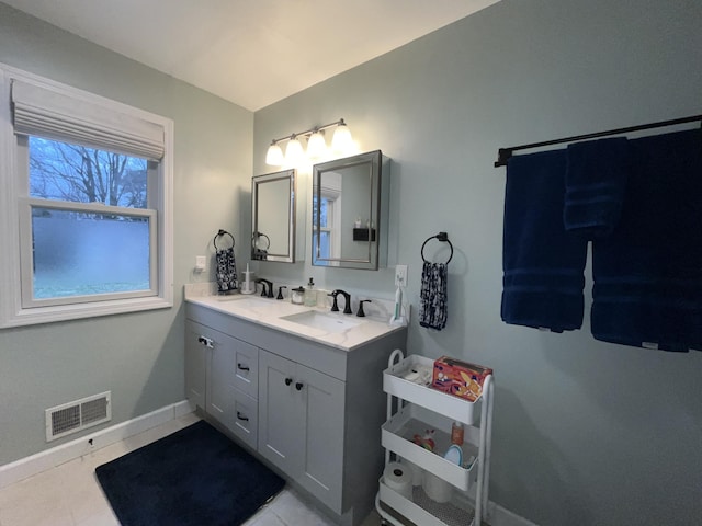 full bath featuring double vanity, baseboards, visible vents, and a sink