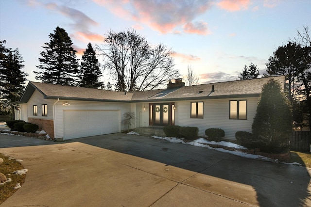 ranch-style home with an attached garage, a chimney, concrete driveway, and brick siding