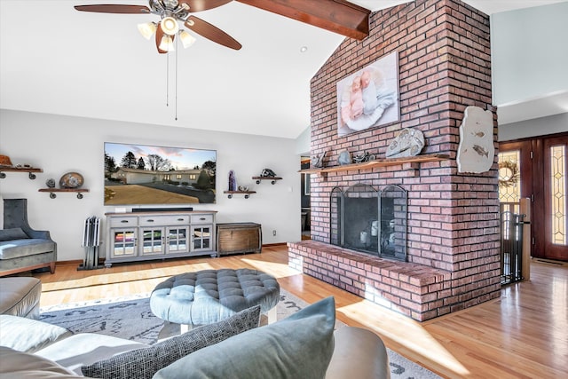 living area with high vaulted ceiling, a brick fireplace, beamed ceiling, and wood finished floors