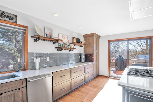 kitchen with light wood finished floors, open shelves, tasteful backsplash, light countertops, and stainless steel dishwasher