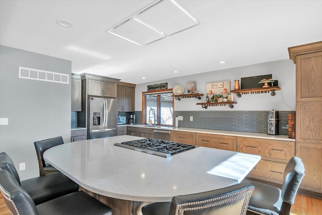 kitchen with visible vents, appliances with stainless steel finishes, a kitchen breakfast bar, open shelves, and backsplash