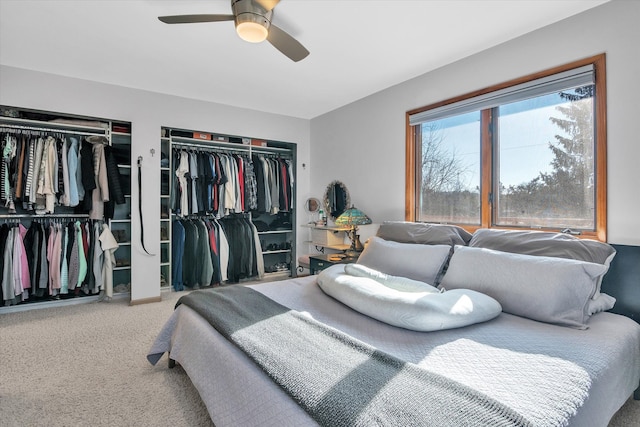 carpeted bedroom featuring ceiling fan and two closets