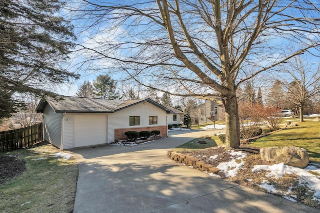 view of side of home featuring a garage, a lawn, concrete driveway, fence, and brick siding