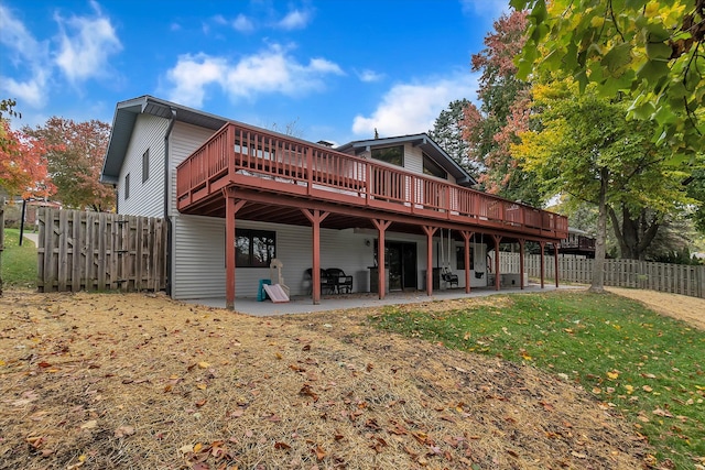 rear view of property with a yard, fence, a deck, and a patio