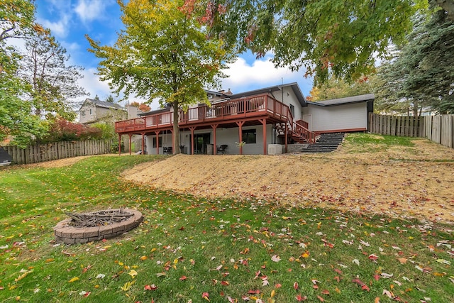 back of property with a wooden deck, a fire pit, a fenced backyard, stairs, and a yard