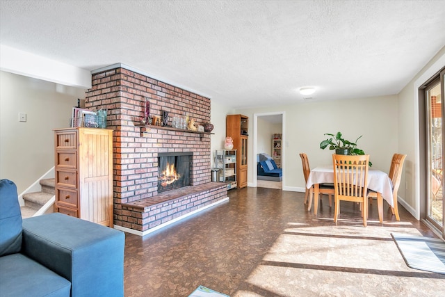 living area with baseboards, tile patterned floors, stairs, a textured ceiling, and a brick fireplace