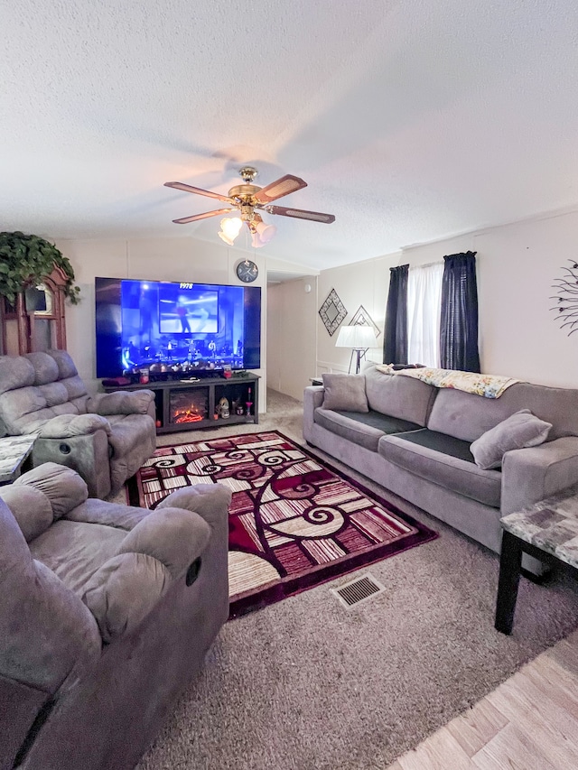 living area featuring lofted ceiling, visible vents, a ceiling fan, a textured ceiling, and wood finished floors