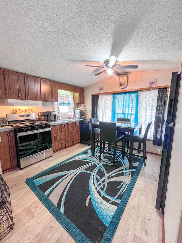 kitchen with stainless steel range with gas cooktop, black dishwasher, light wood-style flooring, brown cabinetry, and a ceiling fan