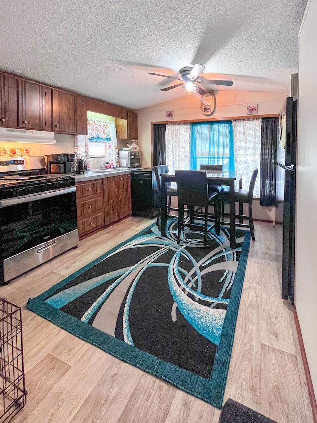 kitchen featuring a textured ceiling, under cabinet range hood, stainless steel range with electric cooktop, black dishwasher, and light wood-type flooring