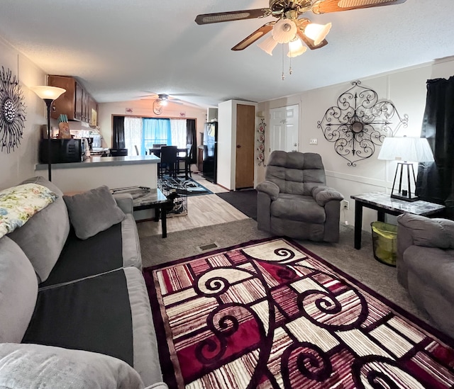 living room featuring lofted ceiling, carpet, ceiling fan, and visible vents