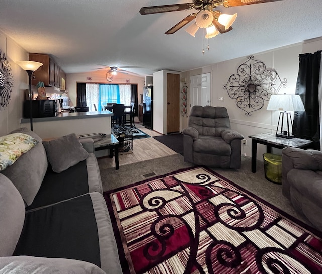 carpeted living room featuring vaulted ceiling, a textured ceiling, and a ceiling fan