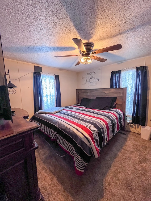 bedroom with carpet, a ceiling fan, and a textured ceiling