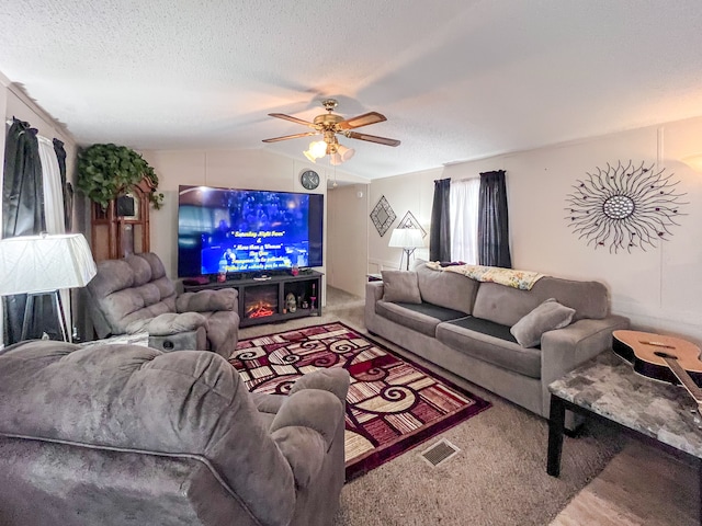 living room with lofted ceiling, ceiling fan, visible vents, and a textured ceiling