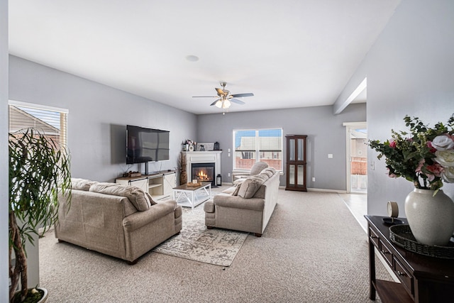 carpeted living area featuring ceiling fan, a glass covered fireplace, and baseboards