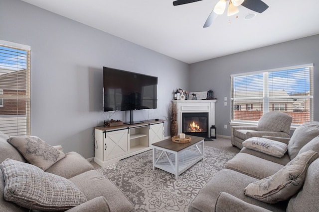 carpeted living area with ceiling fan, baseboards, and a fireplace with flush hearth