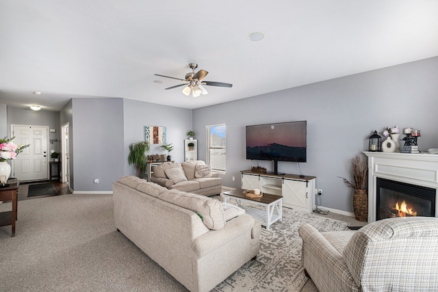 carpeted living room featuring ceiling fan, baseboards, and a glass covered fireplace