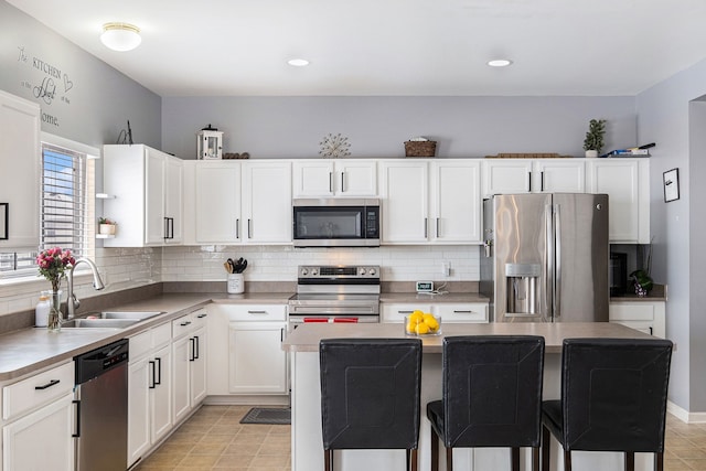 kitchen featuring stainless steel appliances, a sink, decorative backsplash, and a kitchen bar