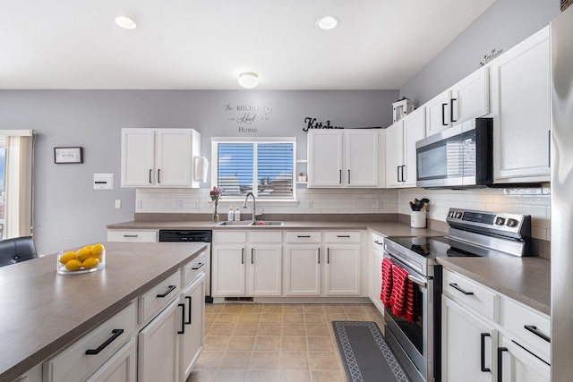 kitchen with stainless steel appliances, backsplash, a sink, and white cabinetry