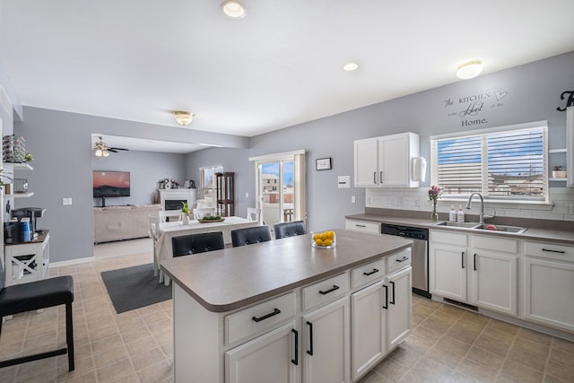 kitchen featuring a fireplace, a sink, a center island, dishwasher, and tasteful backsplash