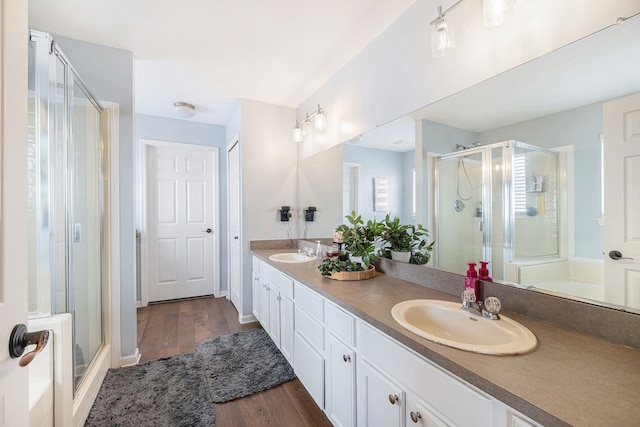 full bath featuring wood finished floors, a sink, a shower stall, and double vanity